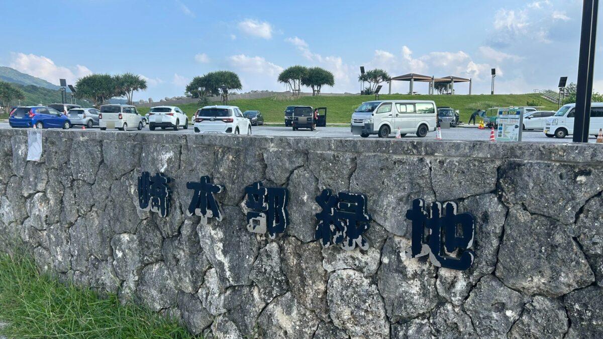 崎本部緑地と書かれた石積みの表示と奥に見える駐車場
